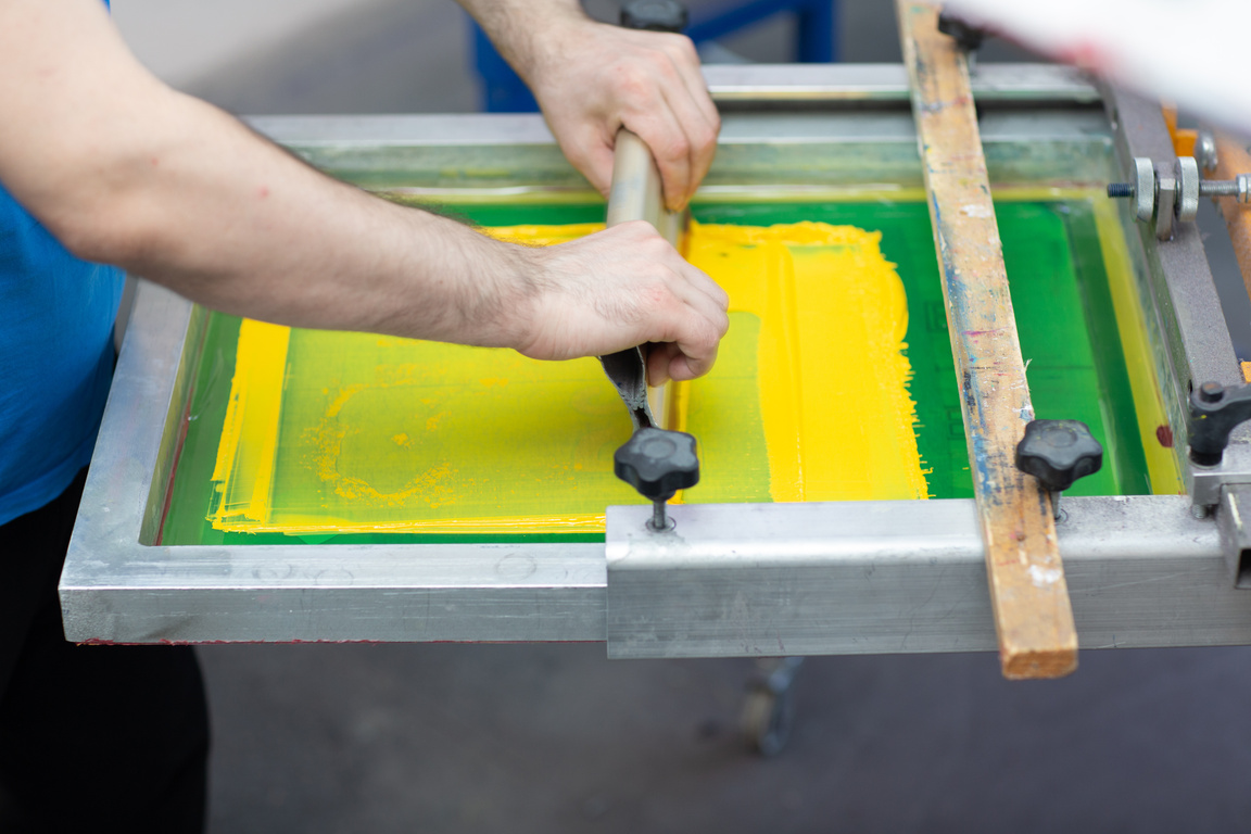 Serigraphy Silk Screen Print Process at Clothes Factory. Frame, Squeegee and Plastisol Color Paints